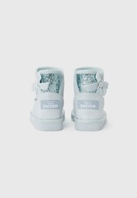 Stivaletti alla caviglia blu chiaro con accenti glitterati, punta rotonda, materiale tessile morbido e un dettaglio a fiocco sul retro. Branding "Frozen" sul lato.