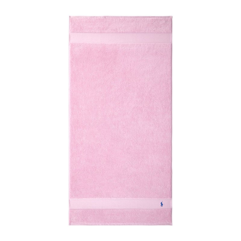 Ροζ πετσέτα από περκάλι με μαλακή υφή, με δύο λεπτές λευκές ρίγες και ένα μικρό μπλε λογότυπο στο κάτω μέρος. Ορθογώνιο σχήμα.