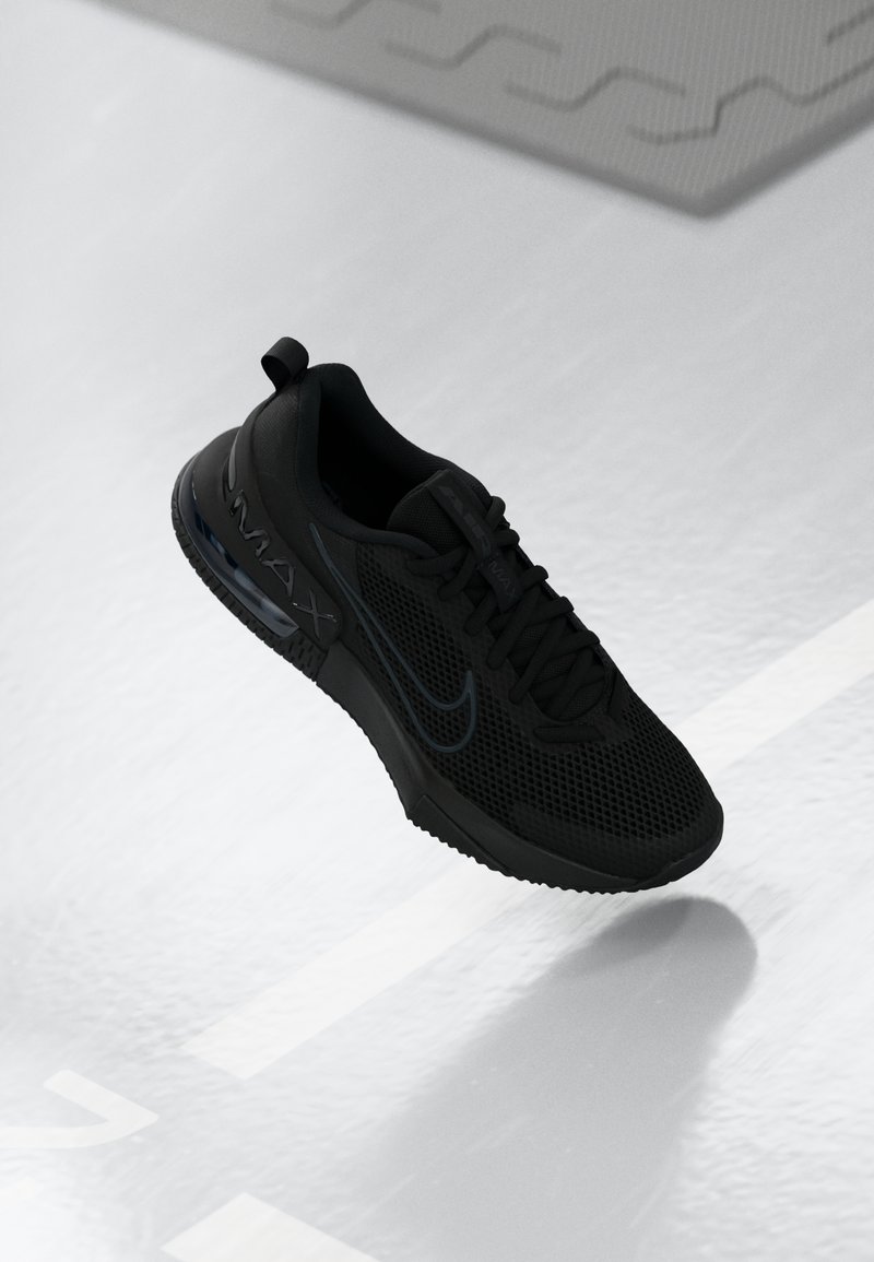 Crne atletske tenisice s gornjim dijelom od mrežastog materijala i gumenim potplatom. Sadrže Nike logo i vidljivu Air Max amortizaciju. Imaju teksturiranu površinu i vezice.