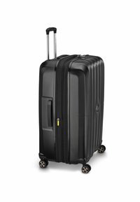 Valigia nera rigida con quattro ruote girevoli, manico telescopico esteso e chiusura a doppia cerniera su uno sfondo bianco.