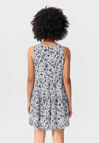 Abito a fiori bianco e blu navy, con design senza maniche, schiena a chiave e gonna a strati. Tessuto morbido e leggero.