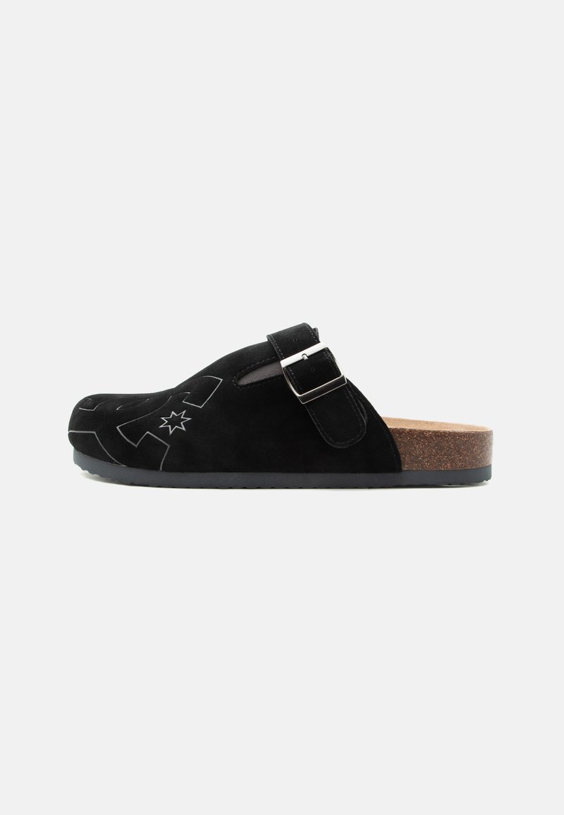 Chaussure noire à enfiler avec semelle en liège, bride à boucle réglable, et motif étoile et géométrique cousu sur le dessus.