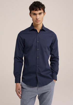 Mörk marinblå skjorta med knappar, spetsig krage, långa ärmar och slim fit. Slät tyg med en subtil lyster och fem knappar fram.