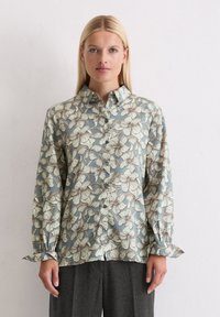 Floral print shirt in soft blue, featuring white and brown flowers. Button-front design with long sleeves and gathered cuffs.