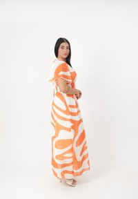Maxikleid mit einem orange-weißen abstrakten Muster, kurzen, flatternden Ärmeln, einem taillierten Oberteil und fließendem Stoff bis zu den Knöcheln.