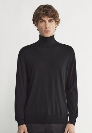 Svart polotröja med långa ärmar, tillverkad av ett slätt, lätt material. Har en figurnära design och ribbade ärmslut och nederkant.