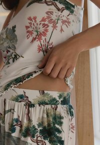 Pyjama set met bloemenprint, gemaakt van een lichte, zachte stof. Het topje heeft verstelbare banden en ruches aan de randen; de broekjes hebben een elastische tailleband.