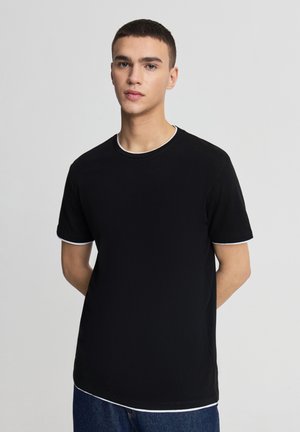 T-shirt nera a maniche corte con bordo bianco su collo e maniche, realizzata in tessuto morbido, con scollo rotondo e vestibilità ampia.