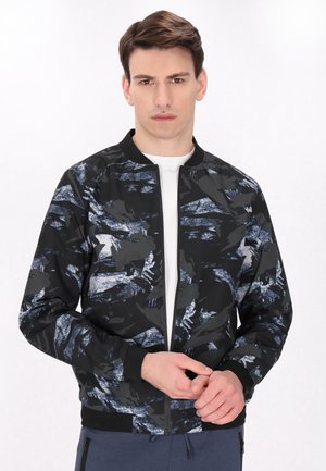 Zwarte bomberjack met een abstract blauw en grijs patroon, geribbelde manchetten en een ritssluiting aan de voorkant. Gemaakt van een gladde, lichte stof.