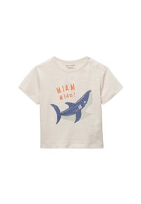 T-shirt en coton beige clair avec un graphic de requin bleu et le texte orange "MIAM Miam !" accompagné d'une forme d'accent verte derrière. Manches courtes.