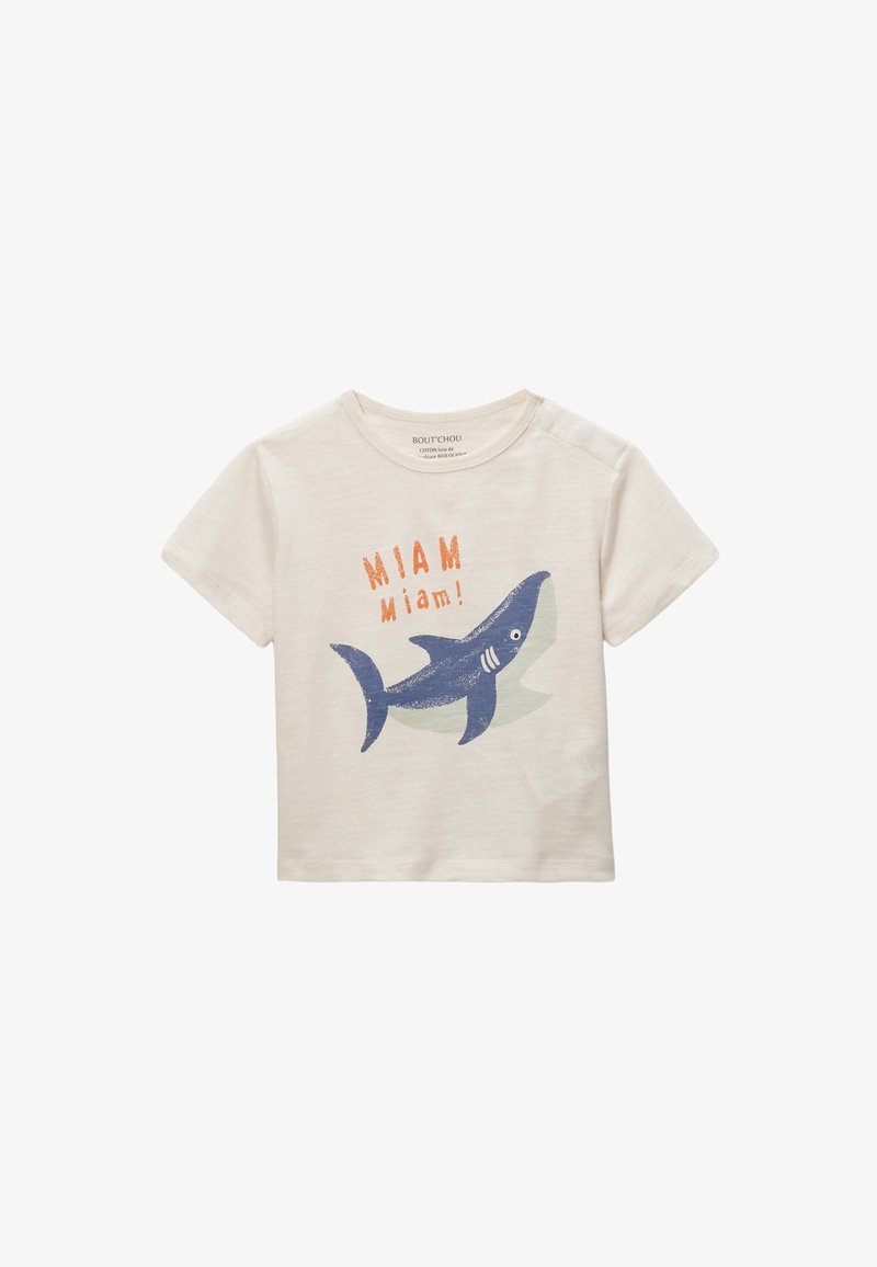 T-shirt en coton beige clair avec un graphic de requin bleu et le texte orange "MIAM Miam !" accompagné d'une forme d'accent verte derrière. Manches courtes.