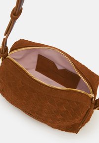 Braune Wildledertasche mit einem strukturierten, gewebten Muster, goldfarbener Reißverschluss und einem weichen rosa Innenfutter. Verfügt über eine kleine Innentasche fürOrganisation.