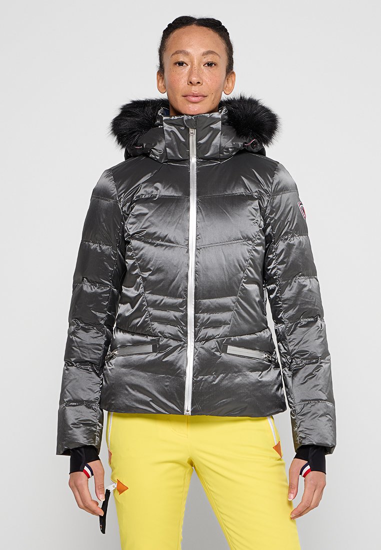 Chaqueta de invierno gris acolchada con capucha de pelo sintético, cremallera plateada, bolsillos con cremallera y puños de contraste, diseñada para brindar calidez y estilo.