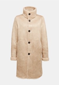 Beige shearlingjacka med hög krage, sju svarta knappar framtill, två sidofickor och mjuka, pälsfodrade ärmslut. Mjuk, strukturerad material.