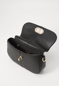 Črna usnjena torbica z zlatim zaklepom. Širok odprtina, en prostor in gladka tekstura. Stranski obroč za pripenjanje trakca.