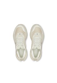 Scarpe sportive beige chiaro con tomaia in rete, dettagli testurizzati e lacci bianchi. Presentano il logo sulla linguetta e una suola morbida e ammortizzata.