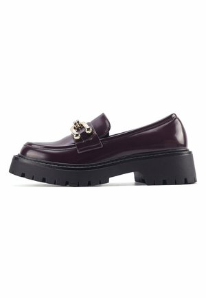 Läikivad burgundia värvi loaferid, millel on dekoratiivne kuldne metallketi detail, paks musta kummitald ja ümar varvas.