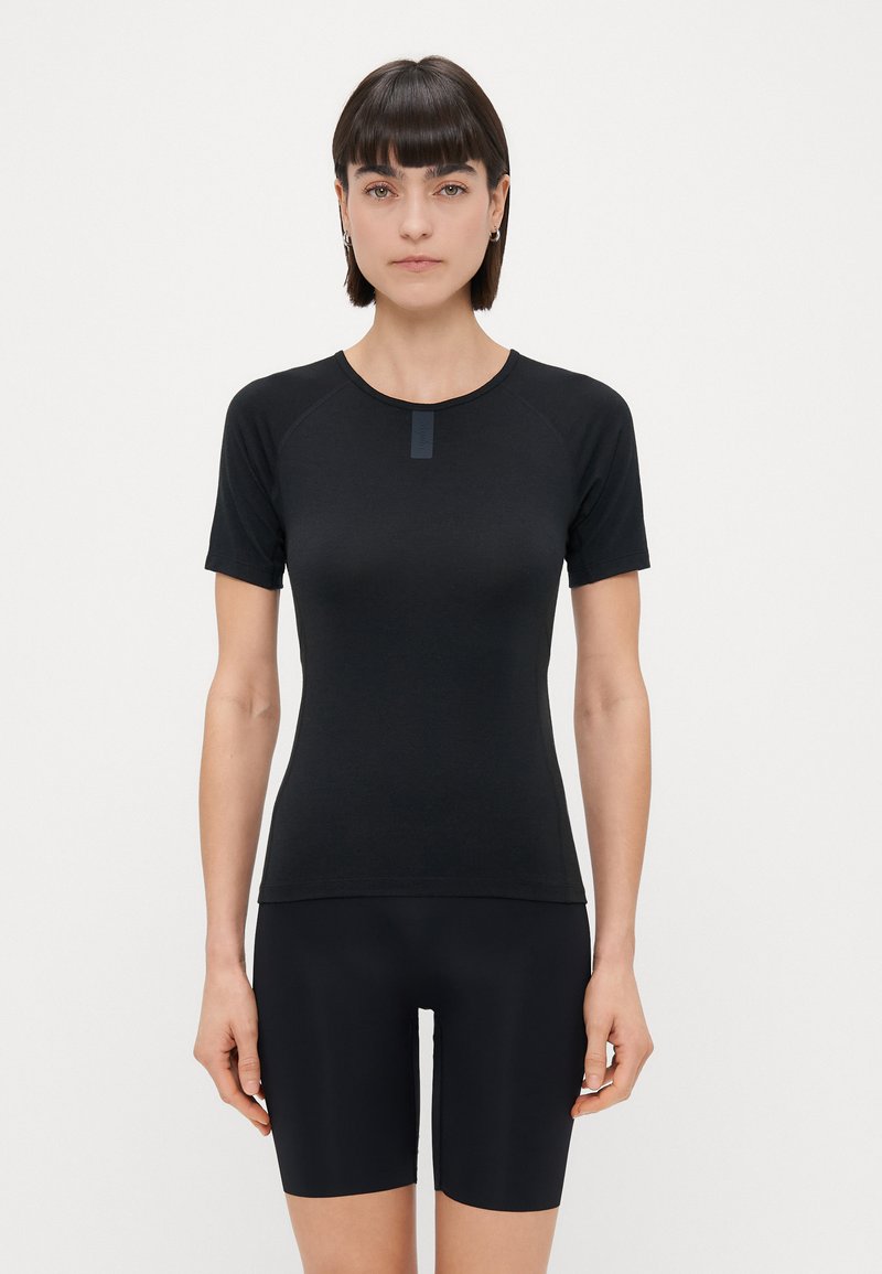 Zwart T-shirt met korte mouwen, ronde hals en raglanmouwen. Soepele textuur met een klein label bij de kraag. Gdragen met een zwarte short.