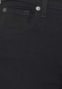 Černé džínové kalhoty z denimu s přední kapsou, stříbrným zapínáním na knoflík a kontrastním prošíváním. Tkanina má hladkou strukturu bez vzorů.