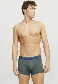 P�ánské boxerky v tmavě zelené látce, s modrým elastickým pasem s logem "JACK & JONES", přiléhavý střih a hladká textura.
