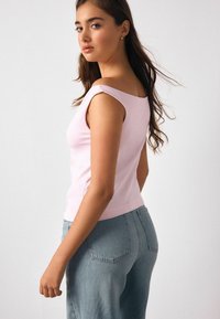 Hele roosa krohvitud topp ruudukujulise kaelusega, lipsuvarrukatega ja siledapinnaline, kombineeritud helesiniste kõrge vöökohaga teksapükstega.