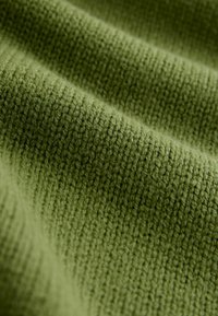 Tela tejida de color verde con un patrón acanalado texturizado. Suave, de peso medio, mostrando un tejido ligeramente desigual y un brillo sutil.