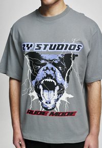 Pilkas medvilninis marškinėlis su šunimi, kuris riaumoja, akcentuotas žaibais. Tekstas sako "RY STUDIOS" ir "RUDE MODE" ryškiomis spalvomis.