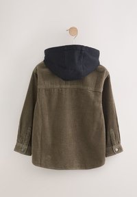 Veste en velours côtelé vert olive avec une capuche bleu marine. Présente une texture côtelée, des poignets boutonnés et un ourlet arrondi. Suspendue sur un cintre en bois.
