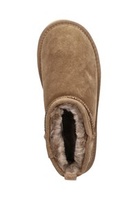 Bruine suède pantoffel met een zachte, donzige binnenvoering. Rond gevormd met een gestikte naad en een kleine hak, voorzien van een trekhaak.