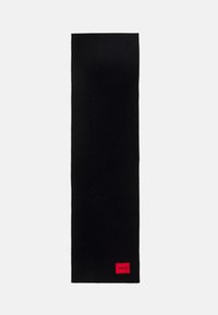 Sort strikket tørklæde, forlænget form, glat tekstur, med et lille rødt mærke med "HUGO" i den ene ende, minimalistisk design.