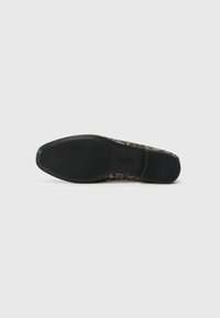 Leopard print slip-on shoe with a flat, textured black rubber sole. Upper features a fabric exterior with a seamless design.
