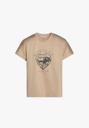 Camiseta beige con un gráfico de corazón que muestra un bisonte y montañas, con el texto "MONTANA 1975" y "SCALPERS" debajo.