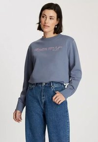 Szara bluza z długim rękawem i okrągłym dekoltem, z r�óżowym napisem. Połączona z wysokim stanem niebieskimi dżinsami. Gładka faktura.