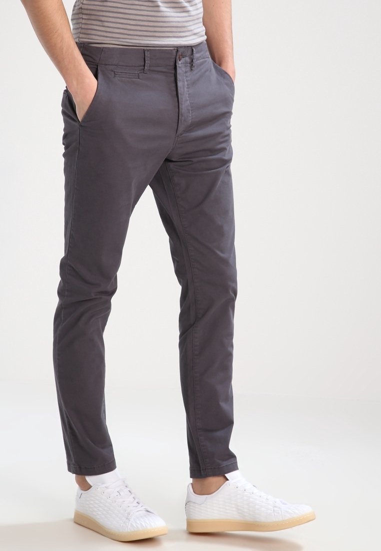 Grå chinos med slim fit, med sidofickor och en subtil textur, kombinerade med vita sneakers och en randig skjorta.