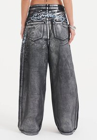Bredde ben jeans i mørkegrå denim med metallisk glans. Har dekorativ broderi på baglommerne og kontrasterende sytråd.