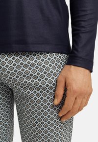 Marinblus med lång ärm ovanför mönstrade leggings i ljusblått med diamant- och blommotif i svart och guld. Slät tygtextur.