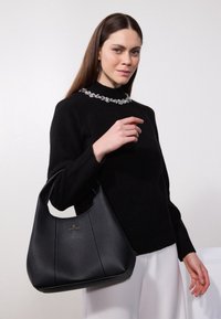 Borsa a tracolla in pelle nera con texture, dotata di una parte superiore arrotondata e dettagli delle cuciture in evidenza. Presenta un sottile logo dorato sul davanti.