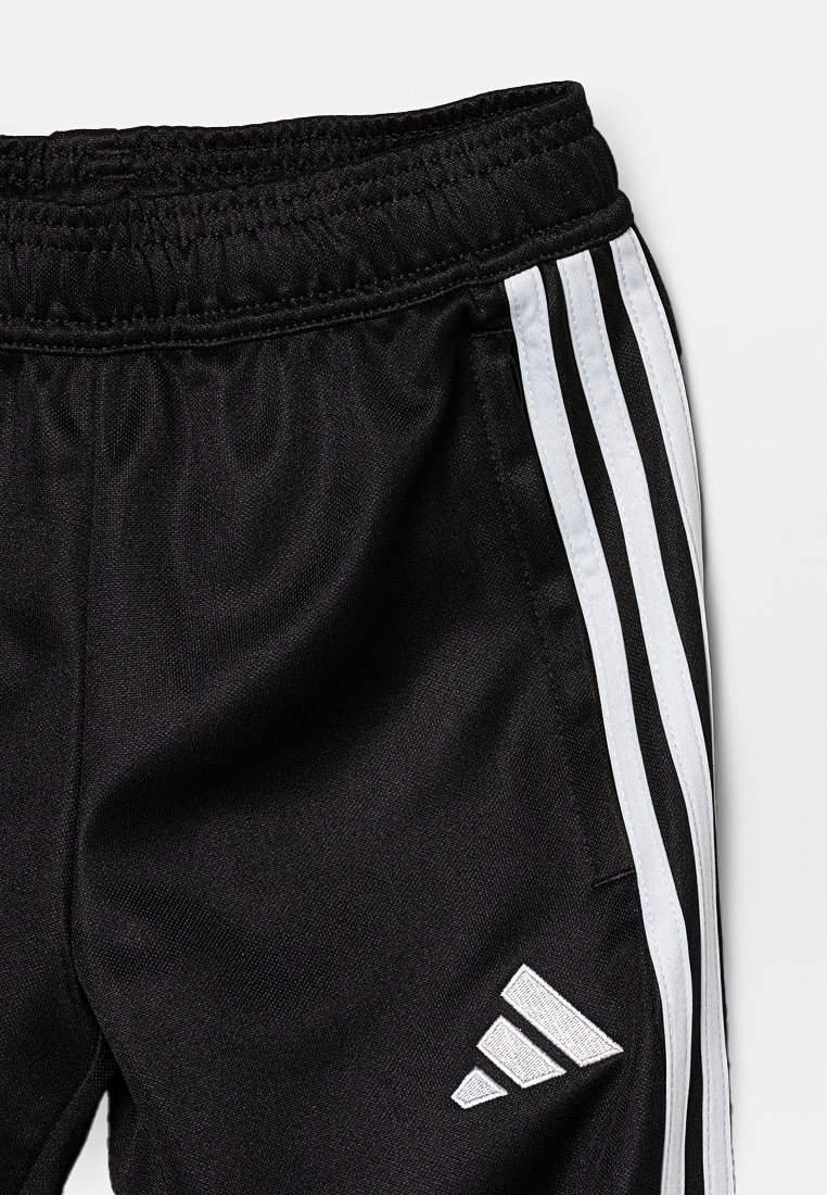 Pantaloni sportivi neri con vita elasticizzata. Presentano tre strisce verticali bianche sui lati e un logo bianco sulla gamba inferiore.