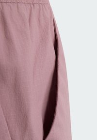 Gros plan sur la poche d'une jupe en tissu mauve clair avec une ceinture froncée et une texture douce.
