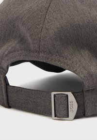 Șapcă gri cu textură chevron, având o curea metalică reglabilă și un detaliu cu logo. Interiorul este negru, evidențiind cusături curate.