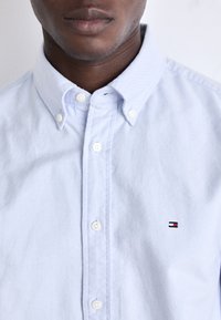 Lichtblauw button-up overhemd van katoen met een geperforeerde afwerking. Bevat witte knopen en een klein geborduurd logo op de borst.