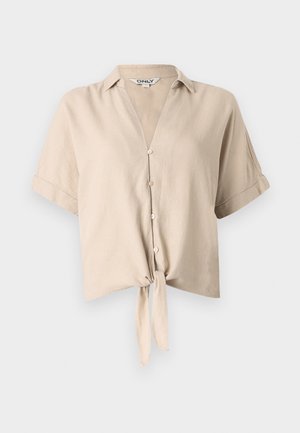 Camiseta beige curta com mangas curtas, colarinho vertical, fecho de botão e detalhe de nó amarrado na frente. Feita de tecido leve.