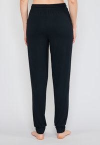 Černé, lehké bavlněné tepláky s elastickým pasem, zúženými nohavicemi a staženými manžetami. Žádné viditelné vzory nebo kovové detaily.