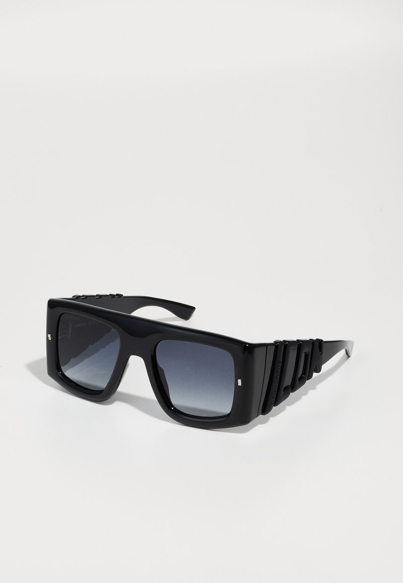 Óculos de sol retangulares pretos com lentes degradê. Armação grossa com laterais texturizadas apresentando sulcos e pequenos detalhes prateados perto das dobradiças.