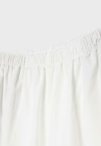 Ceinture élastique blanche avec tissu froncé, gros plan montrant les détails d'un short ou d'un pantalon.