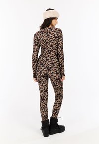 Conjunto de ropa de deporte ajustado con un patrón abstracto multicolor. El material parece elástico con una textura suave. Combinado con botas negras forradas de piel.