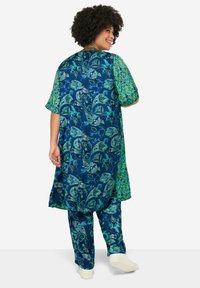 Blue and green patterned outfit with a long tunic and loose pants, featuring paisley designs and short sleeves, made from lightweight fabric.