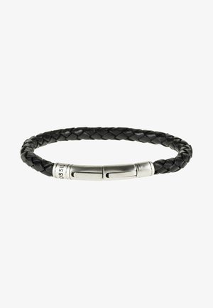 Bracelet en cuir tressé noir avec un fermoir cylindrique en acier inoxydable gravé. Texture lisse avec une forme souple et arrondie.