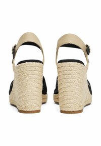 Sandales compensées en espadrille avec tige en tissu noir, talon et plateforme en jute, et bride de cheville beige réglable avec boucle en métal.