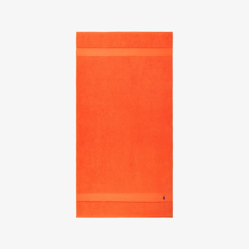 Φωτεινή πορτοκαλί πετσέτα από πετσέτα terry, με απαλό υφή και οριζόντια ταινία στο πάνω μέρος. Μικρό μπλε λογότυπο στο κάτω μέρος.